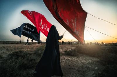 تحت راية العباس عليه السلام، وقفت السيدة زينب، لم تكن الراية قطعة قماش، بل كانت وصيّة أخٍ مضى دون أن يغيب، وعهداً مكتوباً بكفه المبتورة على صفحة الريح: أن تظلّ زينب مصونة، ولو بقي من العباس ظلّ راية فقط