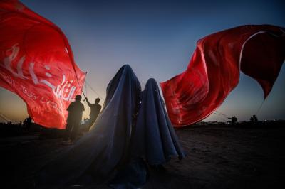 تحت راية العباس عليه السلام، وقفت السيدة زينب، لم تكن الراية قطعة قماش، بل كانت وصيّة أخٍ مضى دون أن يغيب، وعهداً مكتوباً بكفه المبتورة على صفحة الريح: أن تظلّ زينب مصونة، ولو بقي من العباس ظلّ راية فقط