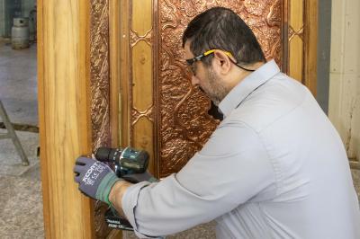 قسم صناعة الشبابيك يباشر تركيب القطع المعدنية على الهيكل الخشبي لباب العباس (عليه السلام)